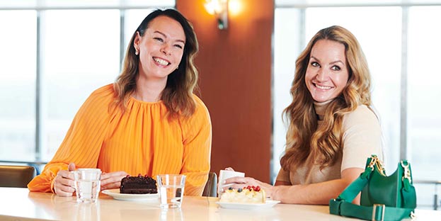 Two women drinking coffee and smiling.