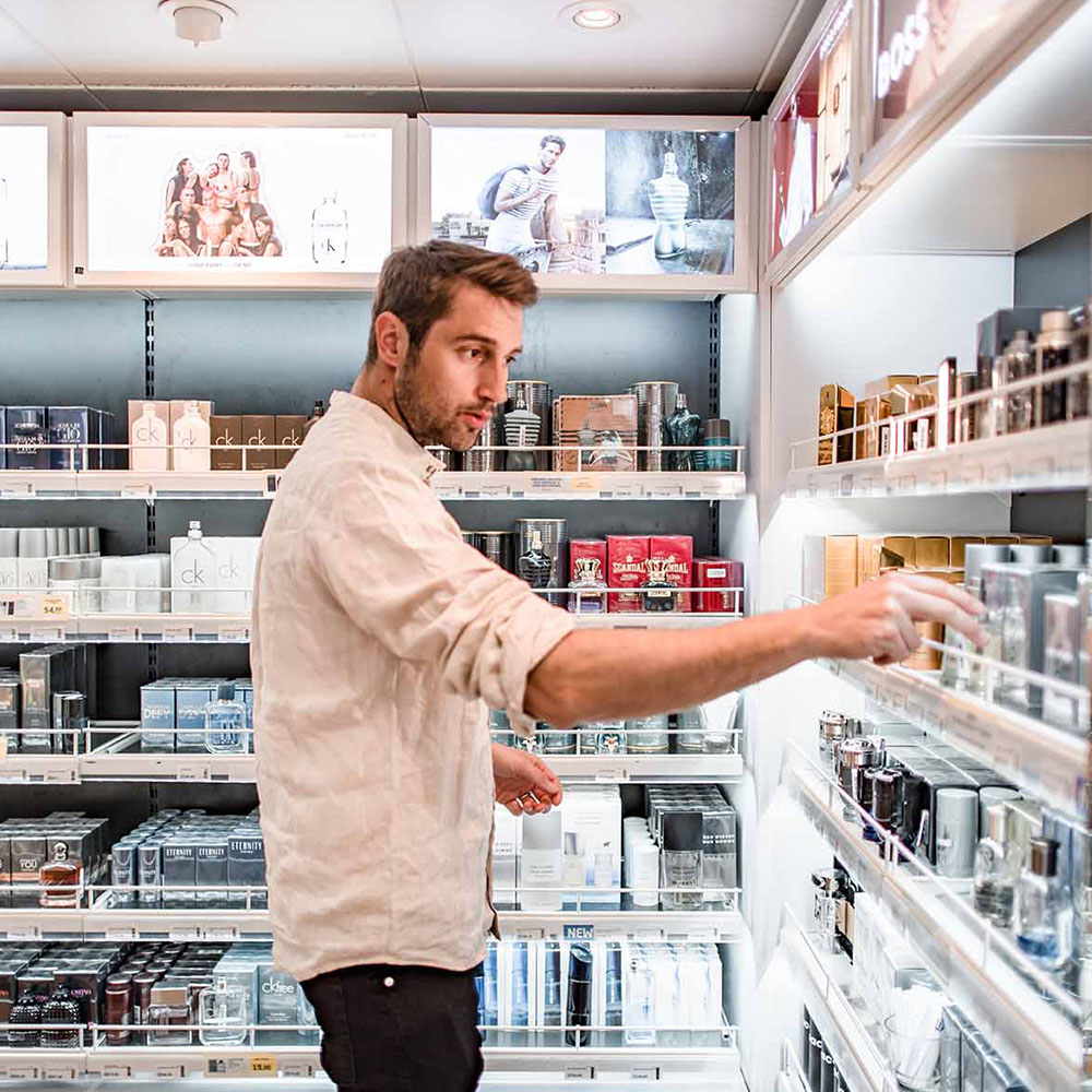 Mies tutkii hajuvesi&auml; laivan myym&auml;l&auml;ss&auml;.