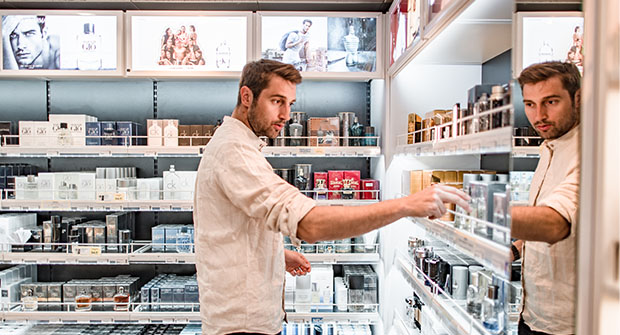 Mies tutkii hajuvesi&auml; laivan myym&auml;l&auml;ss&auml;.